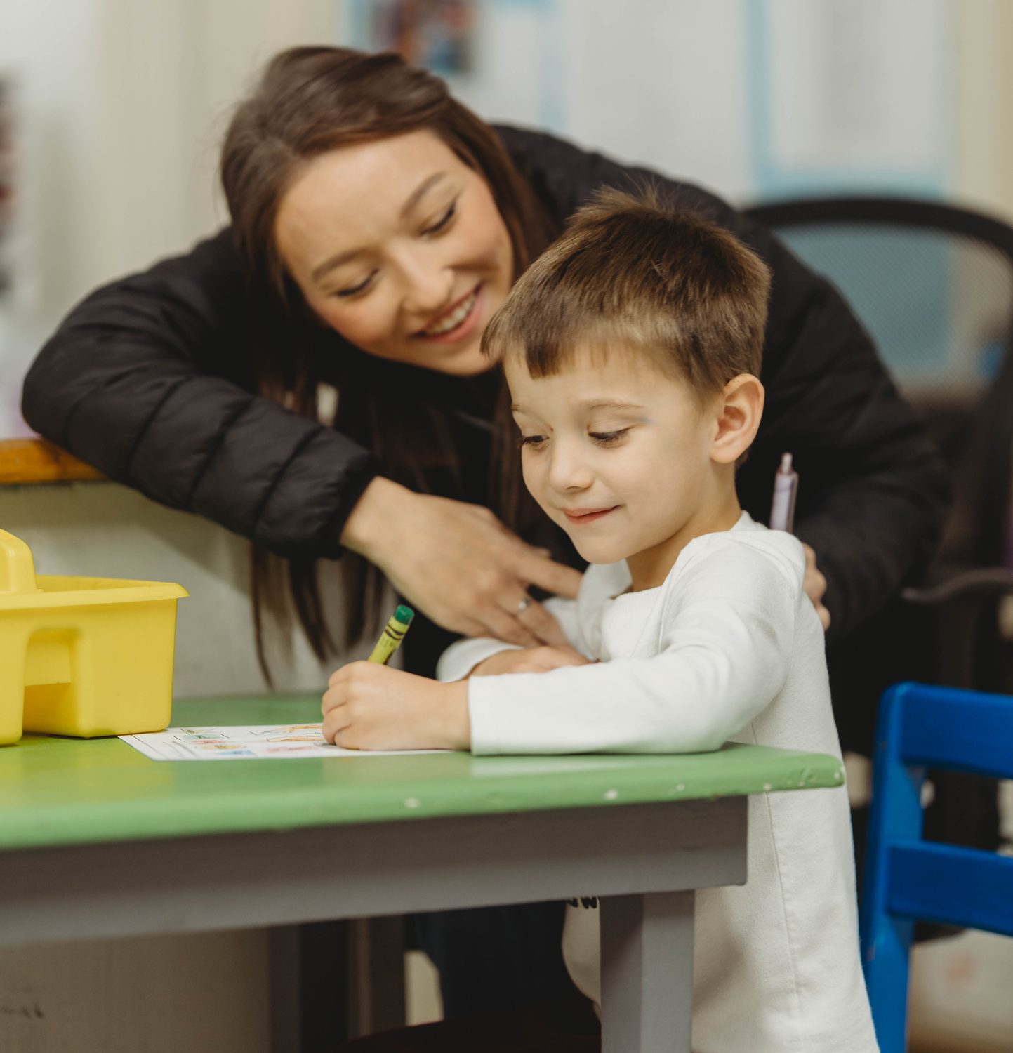 A teacher helps a Pre-K student practice writing at Columbia Academy